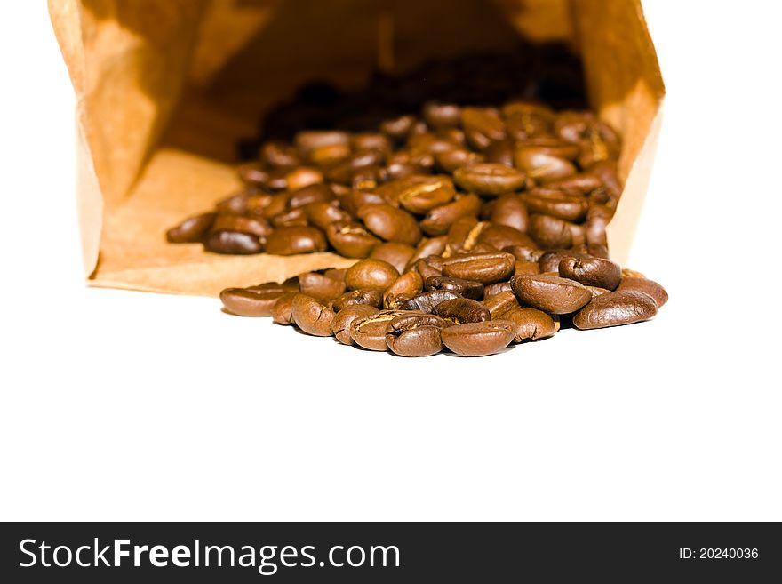 The grains of coffee scattered near a paper package (isolated). The grains of coffee scattered near a paper package (isolated)