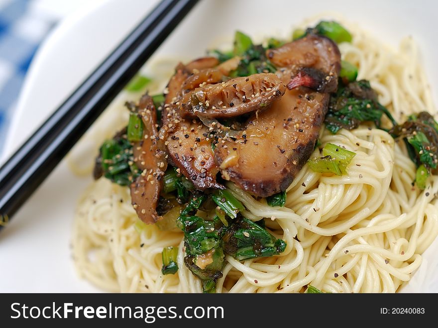 Macro shot of brown mushrooms served on Chinese style yellow noodles. Macro shot of brown mushrooms served on Chinese style yellow noodles.