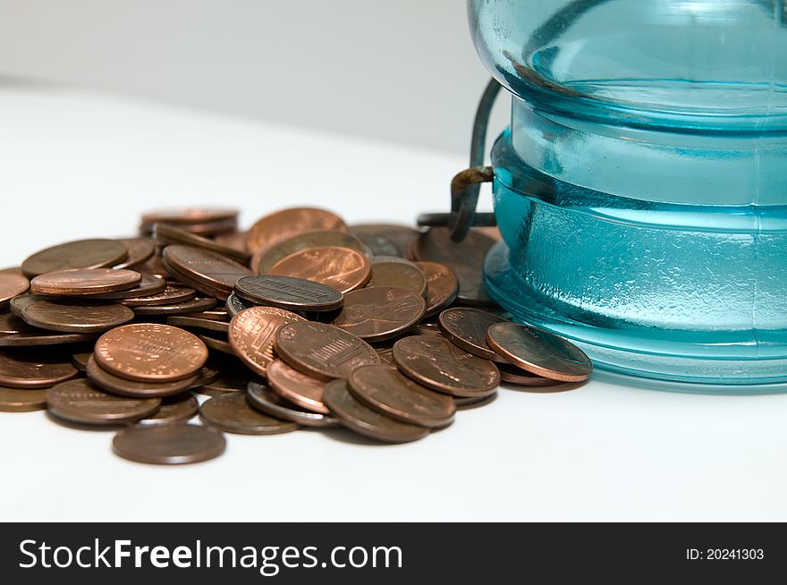 Coins pouring from a coin bank or coin jar. The concept is that folks are opening even their coin jars for their finances. Coins pouring from a coin bank or coin jar. The concept is that folks are opening even their coin jars for their finances.