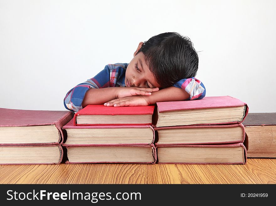 A small kid sleeping over fat books. A small kid sleeping over fat books