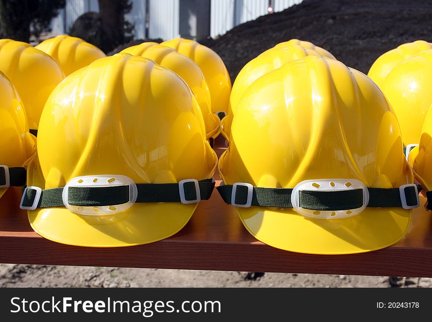 Bunch of construction helmets placed on wooden bench on construction site. Bunch of construction helmets placed on wooden bench on construction site