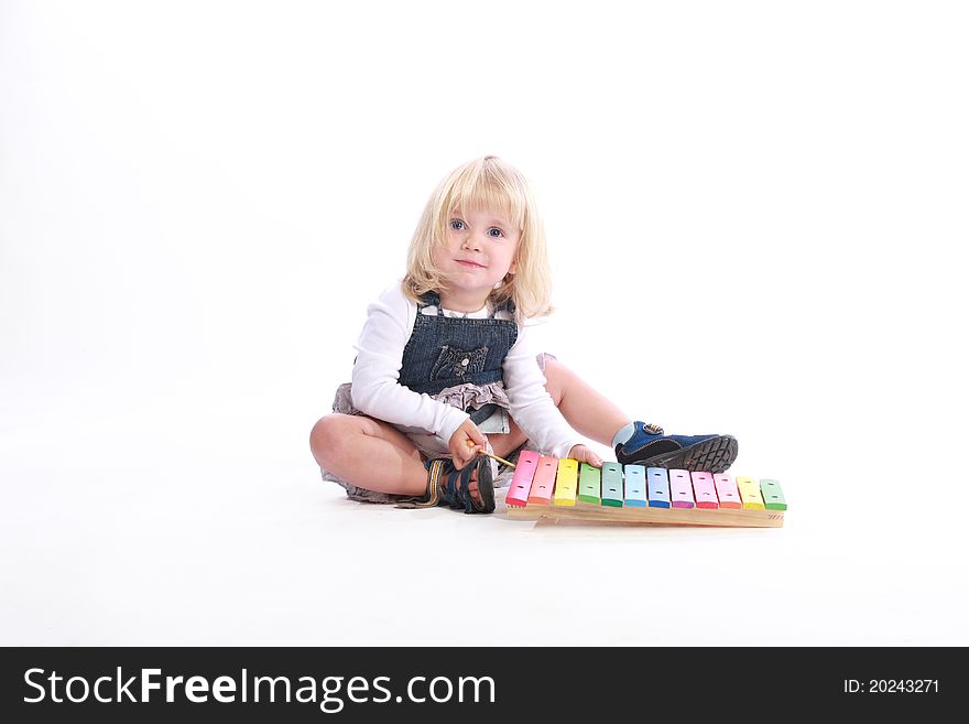 Studio shot of a cute little blonde girl playing a rainbow-colored musical toy. Studio shot of a cute little blonde girl playing a rainbow-colored musical toy.