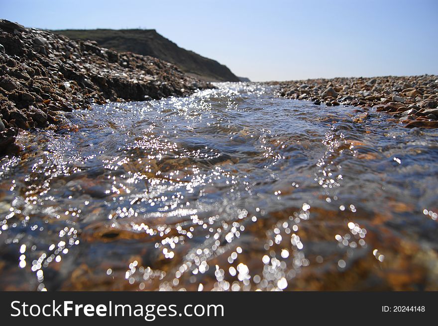 Fresh water stream on a bebble beach leading down to the ocean