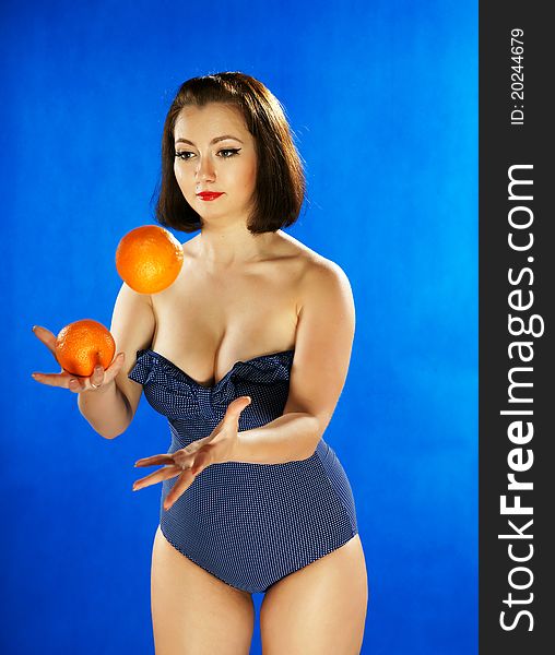 The girl in a bathing suit juggles with oranges