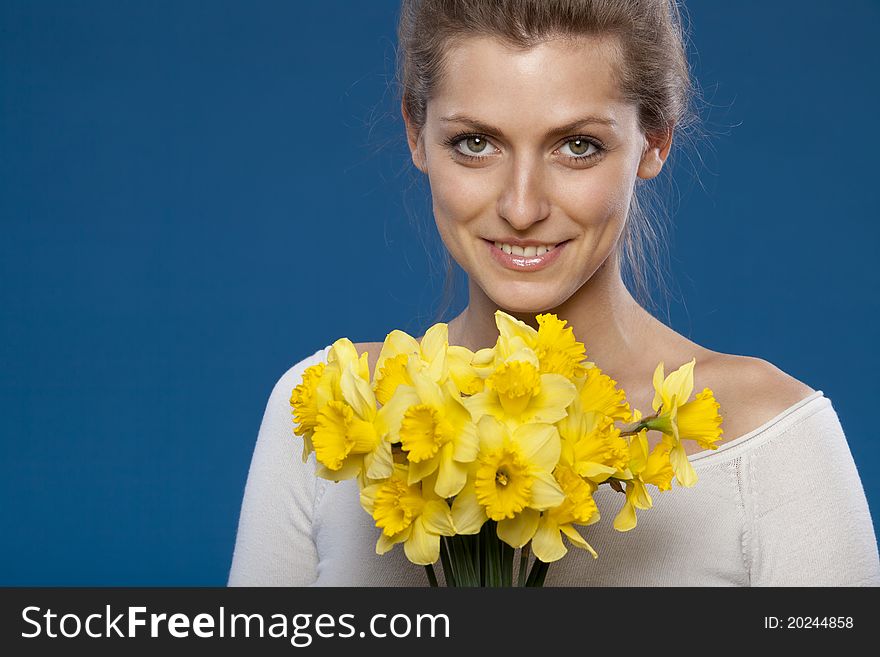 Young female with bunch of flowers on blue background. Young female with bunch of flowers on blue background