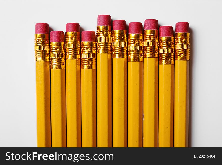 Concept shot of a collection of yellow pencils with red erasers.