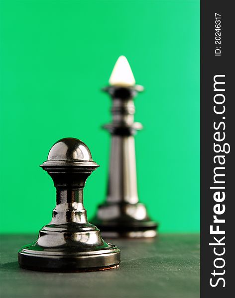 Chess, a pawn and a king in black on a green background. Chess, a pawn and a king in black on a green background