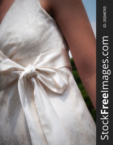 Front torso of a bride wearing white dress with a bow close up. Front torso of a bride wearing white dress with a bow close up