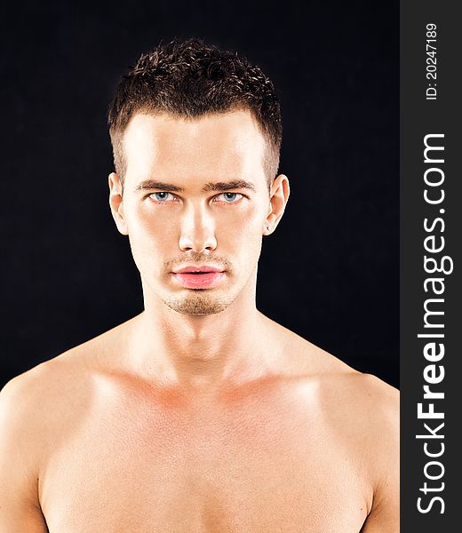 Portrait of a handsome young man with blue eyes on a black background