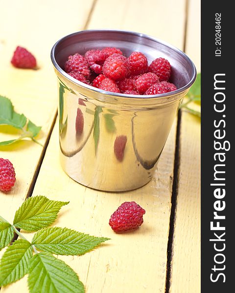 Pile of Raspberries in iron glass on wooden background