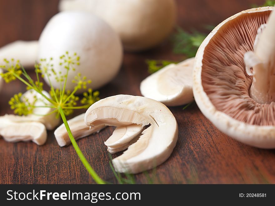 Mushrooms cut and whole on wooden background. Mushrooms cut and whole on wooden background