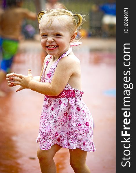 A young girl plays in the sprinklers at a waterpark. A young girl plays in the sprinklers at a waterpark