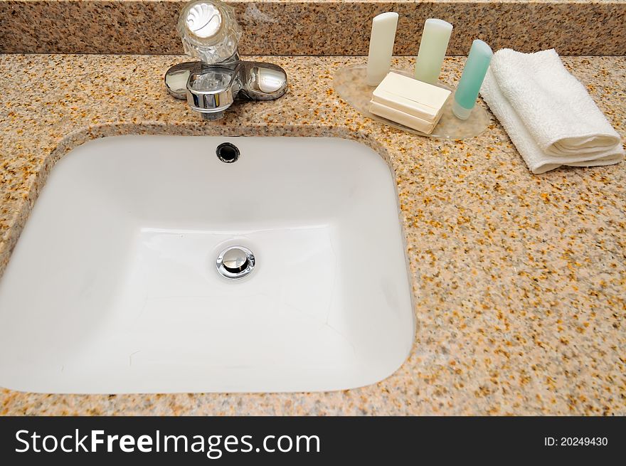 Hand wash basin with shampoo, soap and towel.