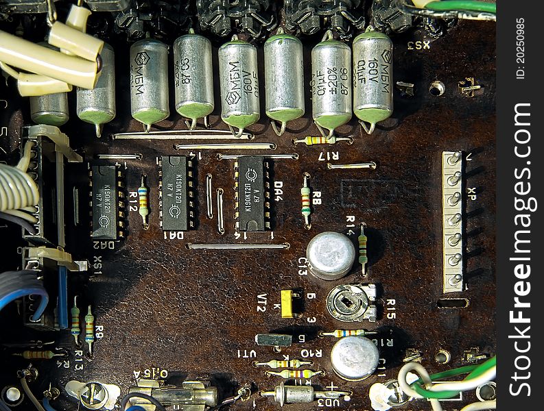 Old and dark microcircuit board with transistors, capacitors, chips and other elements