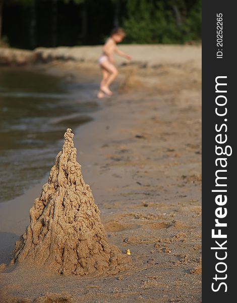 Sand castle on beach with playing child