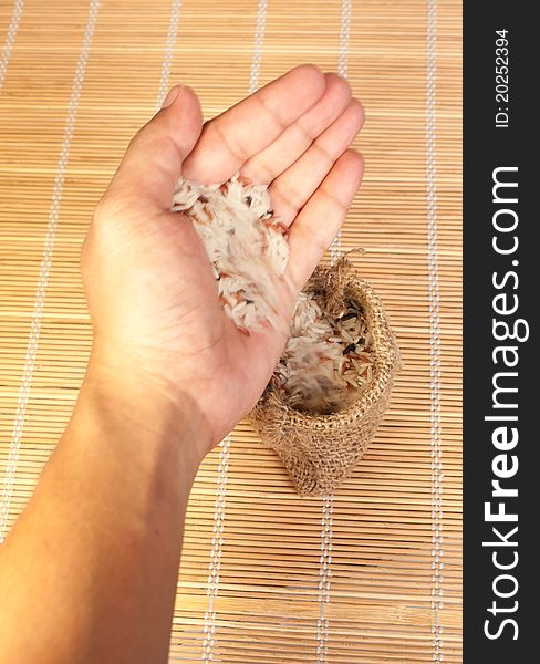 Hand pouring raw rice to woven bag for food concept