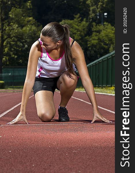 Young woman in sprinting position on the track