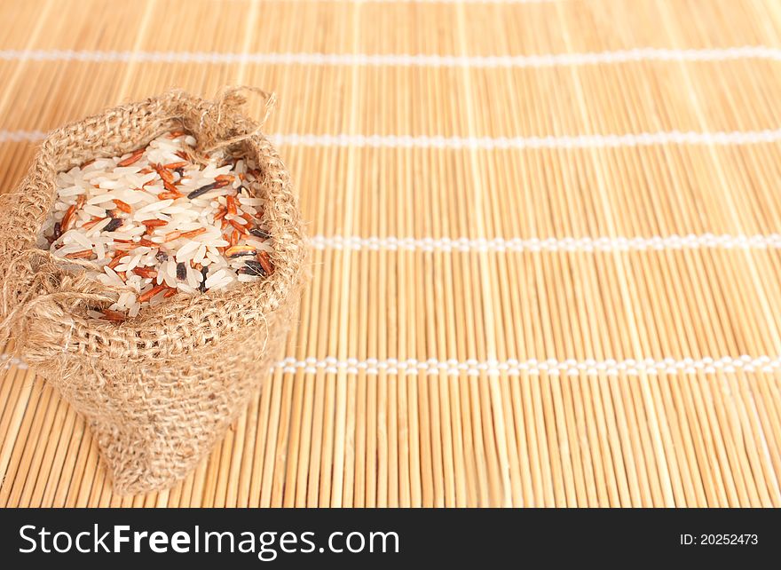 Raw rice in woven bag on bamboo pad for food industry or agriculture concept