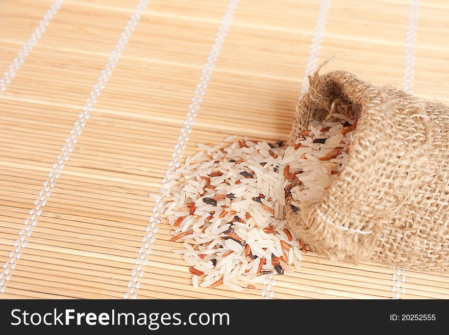 Raw rice pouring frim woven bag from bamboo pad