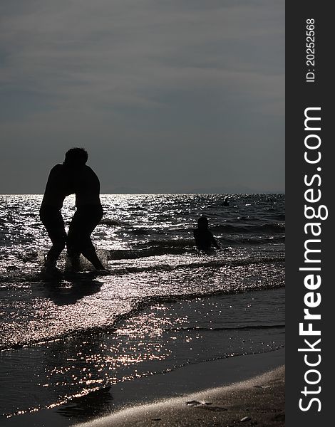 Two boys are playing on the beach at sunset. Two boys are playing on the beach at sunset