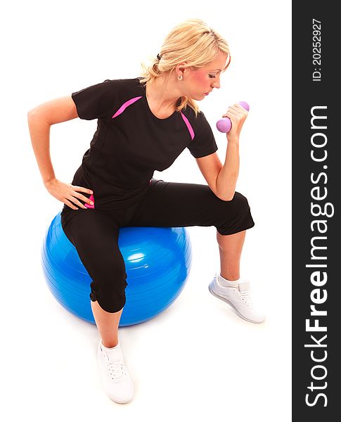 A young female dressed in black exercise clothes performing an arm curl on a gym ball. A young female dressed in black exercise clothes performing an arm curl on a gym ball