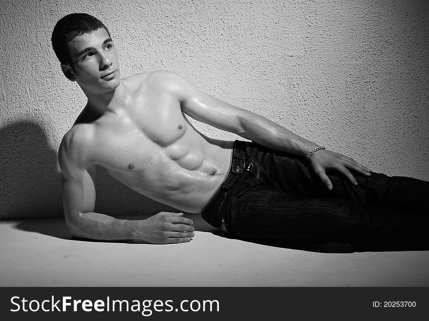 Portrait of muscular young man, black and white studio background.