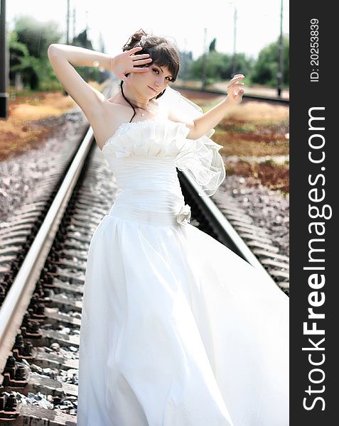 A beautiful bride stands on the railroad