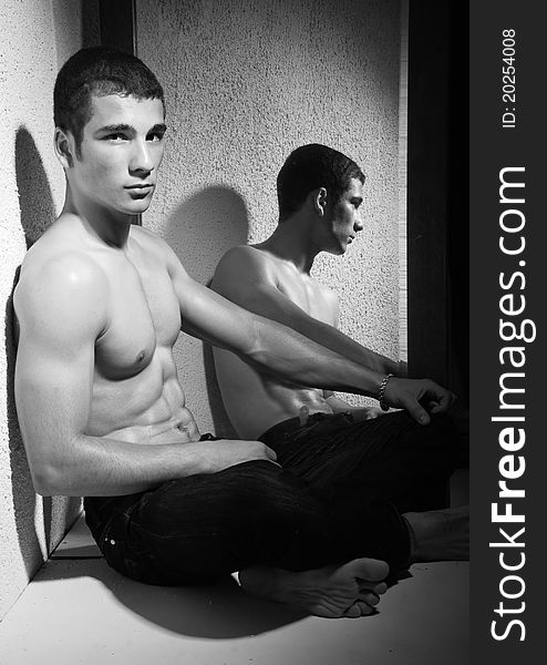 Black and white half body portrait of muscular young man reflected in full length mirror. Black and white half body portrait of muscular young man reflected in full length mirror.