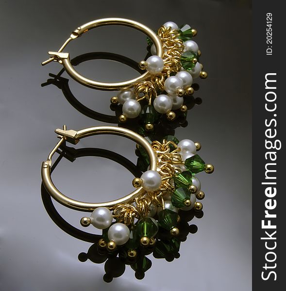 Close up of handmade earrings with gemstones over black background