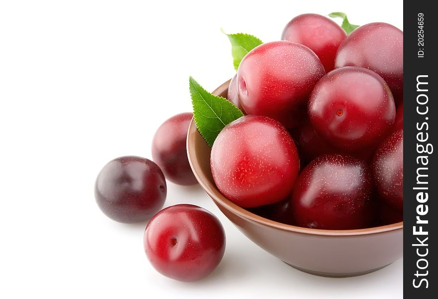 Ripe plums in a plate on a white background