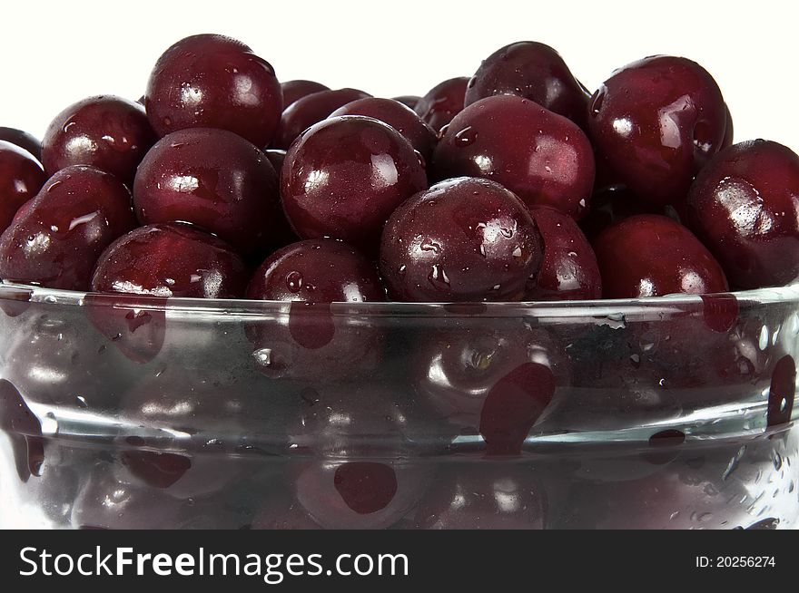 Red sweet cherries in glass plate on a white background