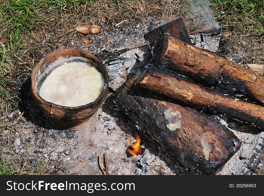 Soup in ceramics pot and firewood