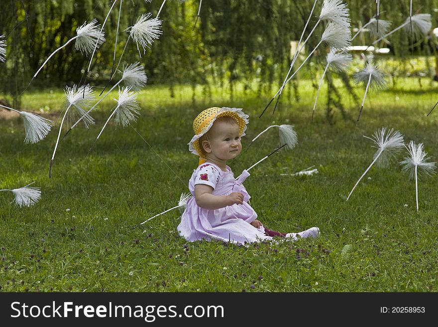 1 year old baby sitting in meadow with flying dandelion seeds. 1 year old baby sitting in meadow with flying dandelion seeds