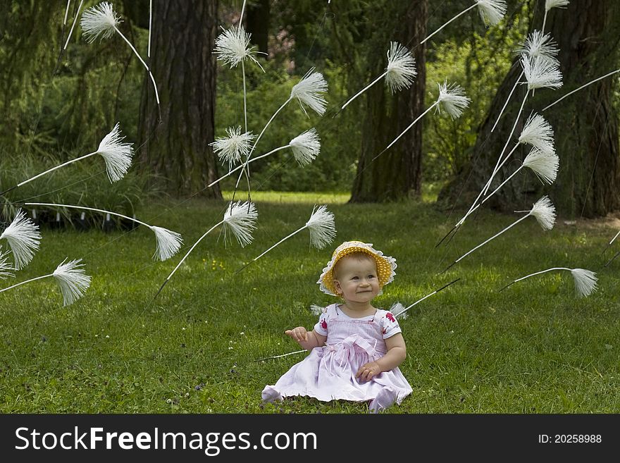 1 year old baby sitting in meadow with flying dandelion seeds. 1 year old baby sitting in meadow with flying dandelion seeds