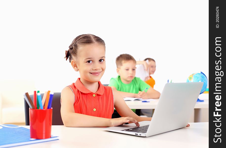 Portrait of a young girl working on laptop at school at the desk.