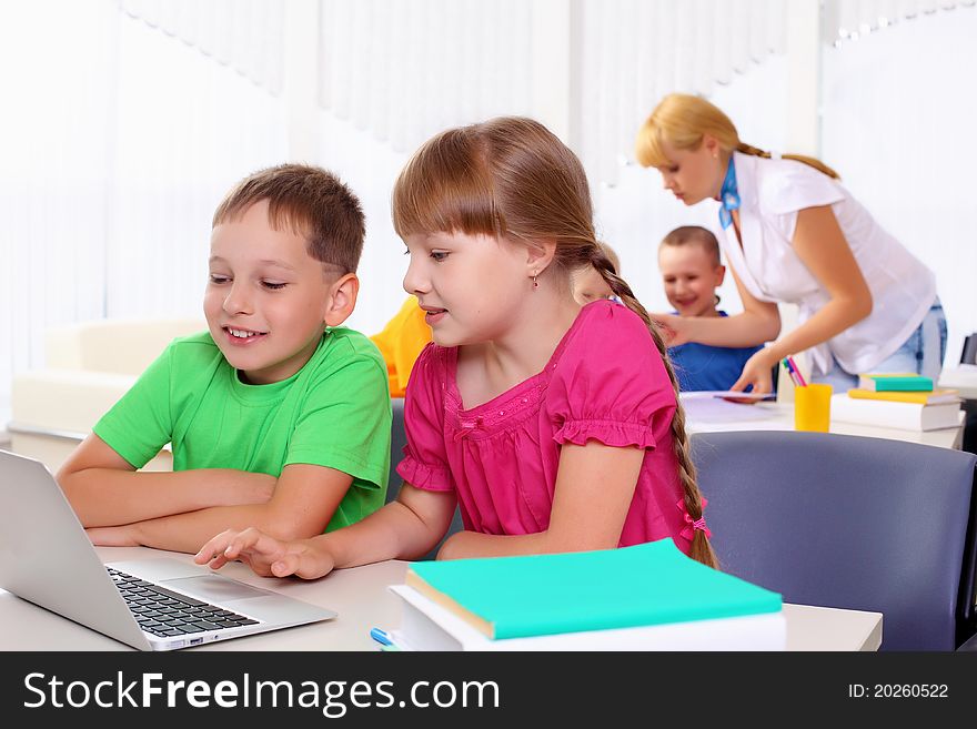 Boy and girl working together on a laptop at school.