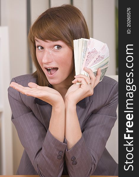 Happy business woman with stack of money in office