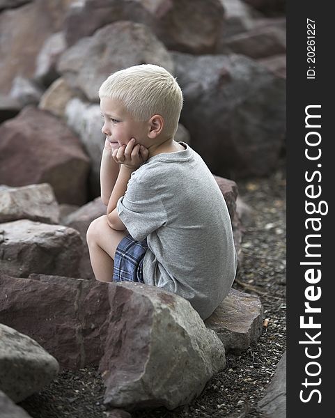 Young blonde boy outdoor, among big stones. Young blonde boy outdoor, among big stones