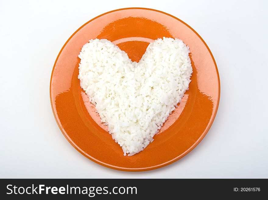 Heart shaped white rice on an orange ceramic plate. Heart shaped white rice on an orange ceramic plate