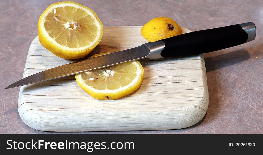 A Lemon Sliced on a Cutting Board with a Knife. A Lemon Sliced on a Cutting Board with a Knife