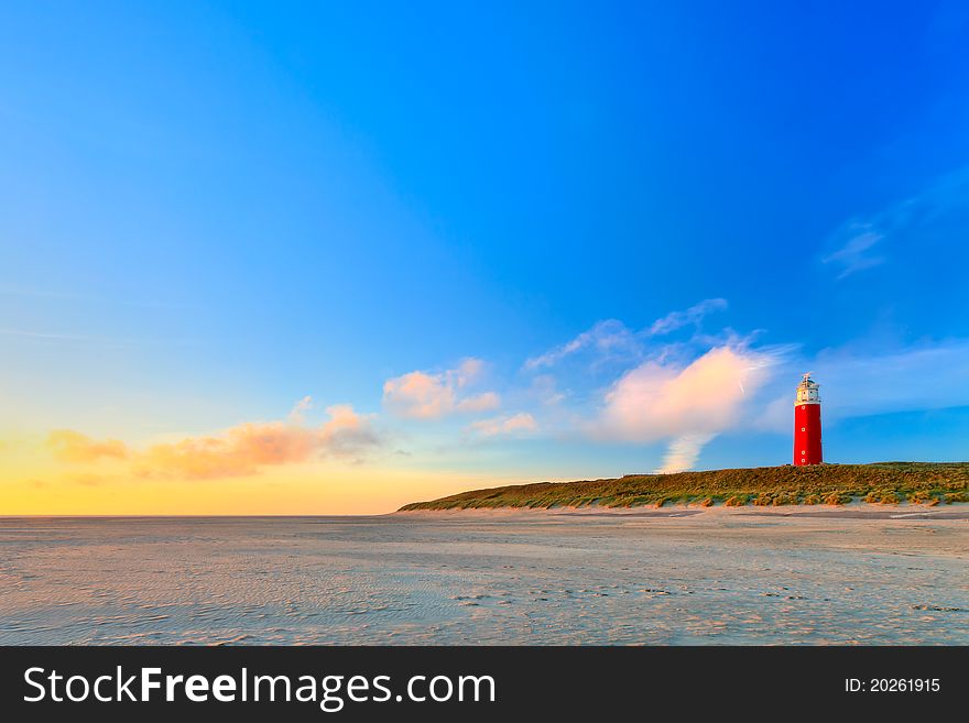 Seaside with sand dunes and lighthouse at sunset