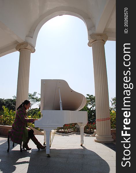 A woman playing piano in the arched corridor.