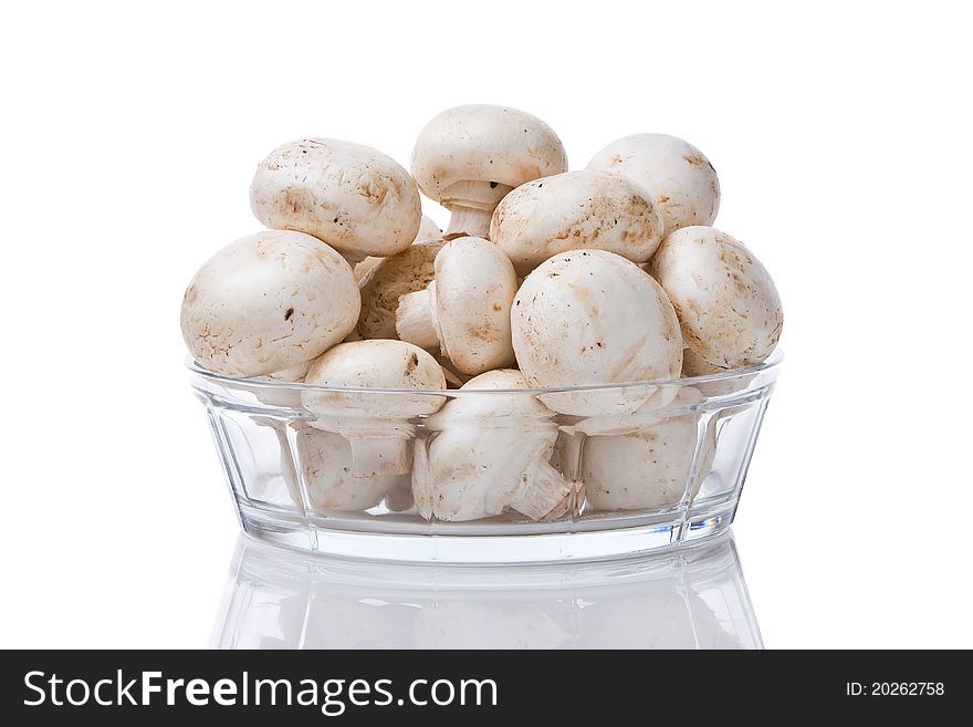 Bunch of mushrooms in a glass bowl against a white background