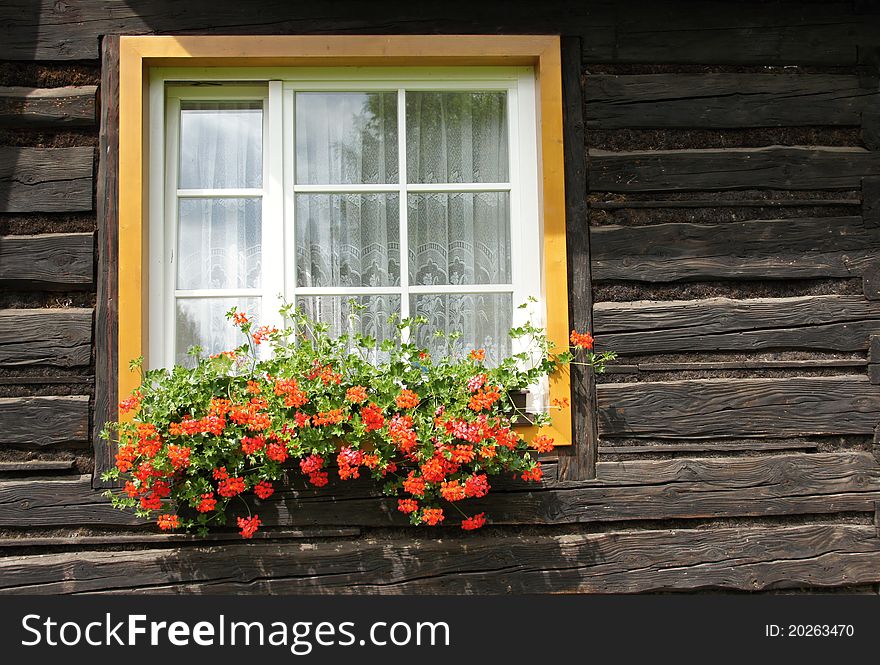 Window with geranium in log hut. Window with geranium in log hut.