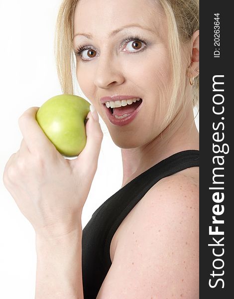 Attractive blond caucasian woman holding a green apple near mouth ready to take a bite. Attractive blond caucasian woman holding a green apple near mouth ready to take a bite