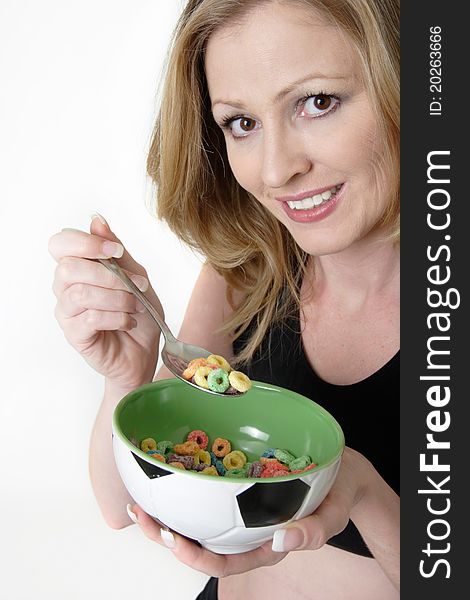Attractive blond caucasian woman eating a bowl of colourful cereal from a green bowl. Attractive blond caucasian woman eating a bowl of colourful cereal from a green bowl