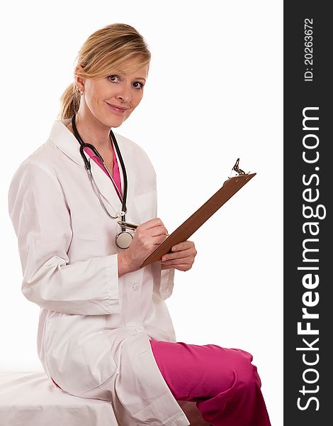 Attractive lady blonde female doctor holding chart wearing pink scrubs and white lab coat. Attractive lady blonde female doctor holding chart wearing pink scrubs and white lab coat