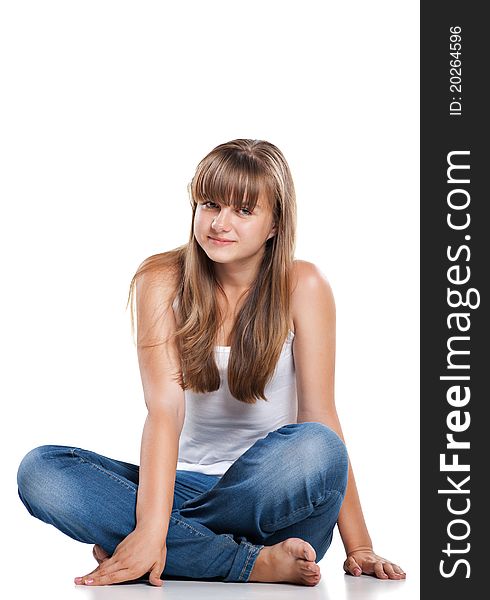 Smiling teenager girl sitting in studio on white background