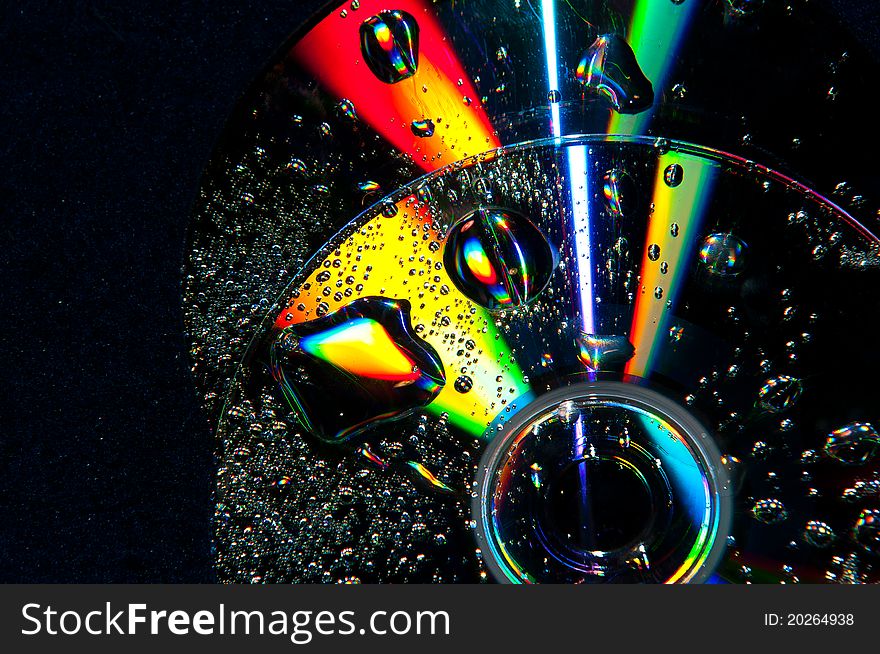 A compact disk with water droplets on it. A compact disk with water droplets on it