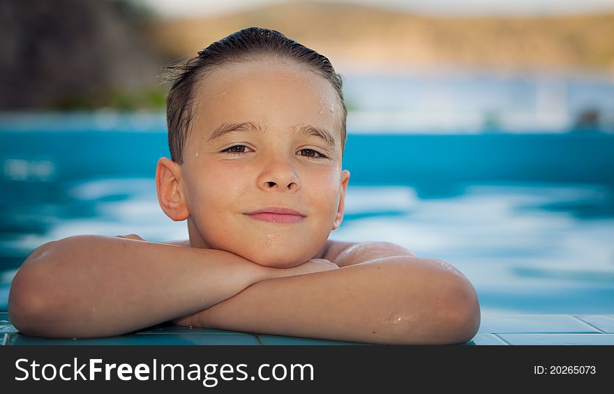 Portrait of a boy having a break from swimming in the pool at the end of the day with sea and mountains in the background. Portrait of a boy having a break from swimming in the pool at the end of the day with sea and mountains in the background